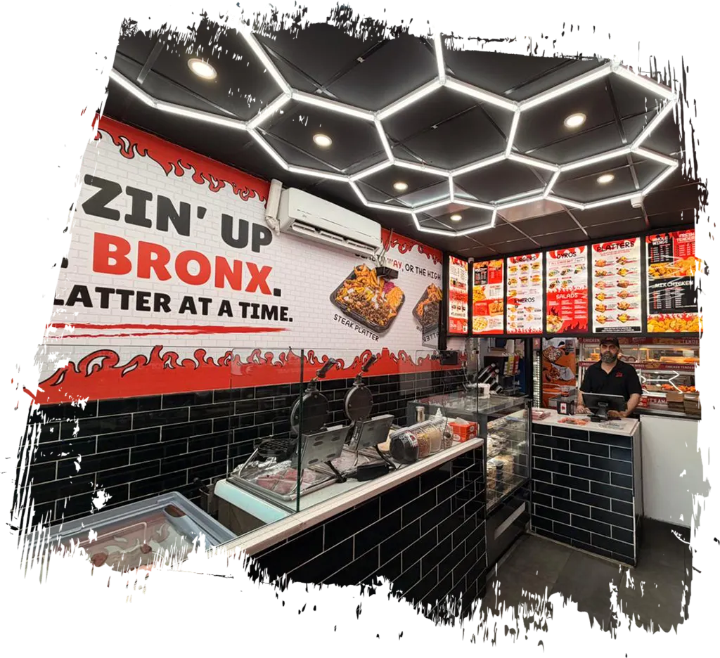 Interior of Blazin Chicken and Gyro in the Bronx featuring red and black decor, illuminated ceiling lights, menu boards, and the service counter.