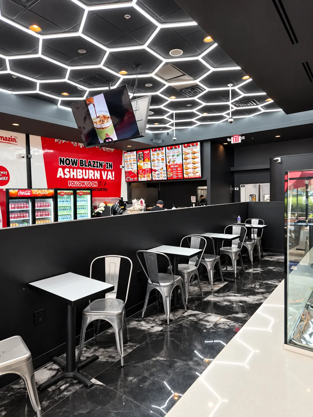 Dining room at Blazin Chicken & Gyro, a halal restaurant in Ashburn VA, with hexagon ceiling lights, metal chairs and the Now Blazin in Ashburn sign above the counter