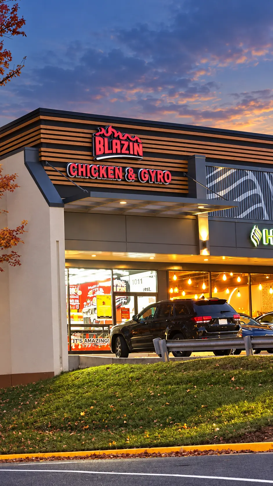 Blazin Chicken & Gyro storefront at dusk, a halal restaurant on Main St in Fairfax VA, with the lit red sign and cars parked out front in the Westbriar Center